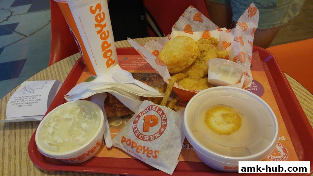 A tray of Popeyes fried chicken, biscuits, fries, coleslaw, and a drink.
