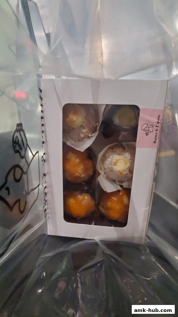 A box of assorted pastries from Butter & Cream Bakery, featuring various toppings and fillings.