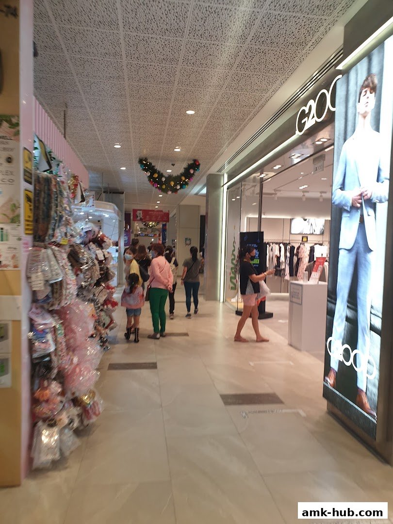 A shopping mall corridor with people walking past the G2000 store.