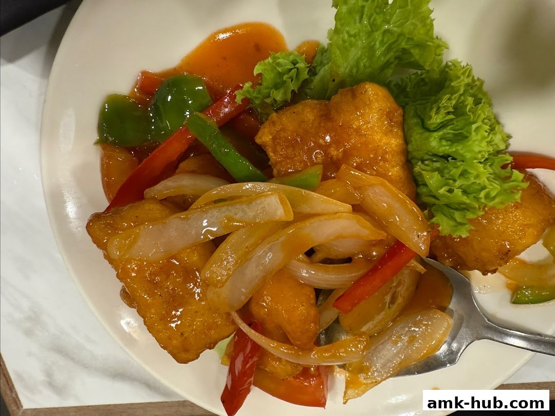 A plate of sweet and sour fish with vegetables and lettuce garnish.