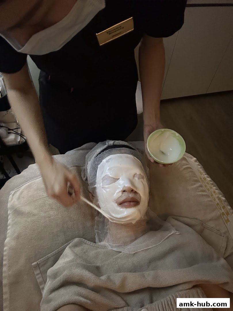 A person receives a facial treatment with a white mask being applied.