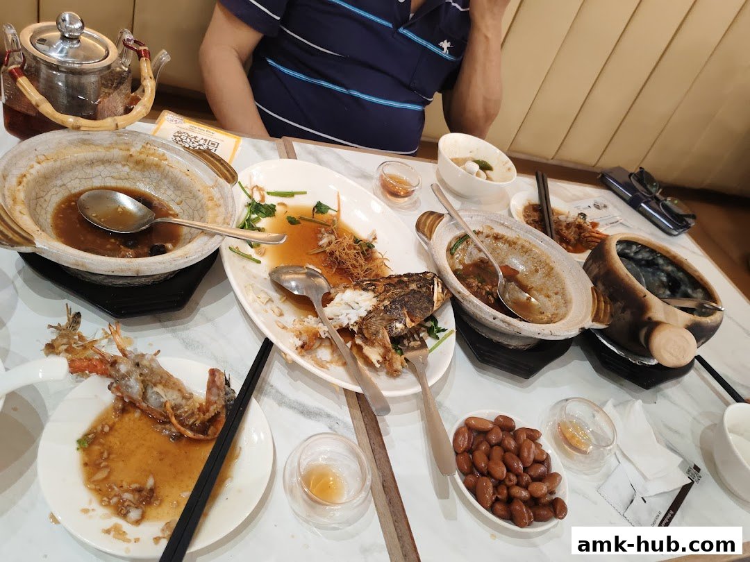 A table with remnants of a meal, including fish, shrimp, and a teapot.