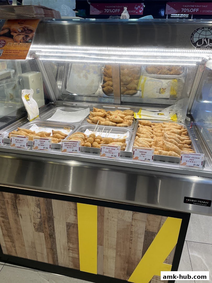 A display case filled with various savory pastries and fried snacks, labeled with prices.