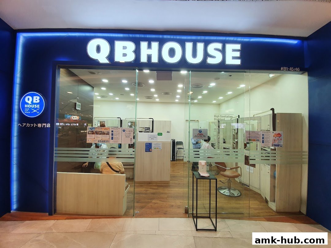 The exterior of QB HOUSE, a hair salon, with its prominent signage and glass entrance.