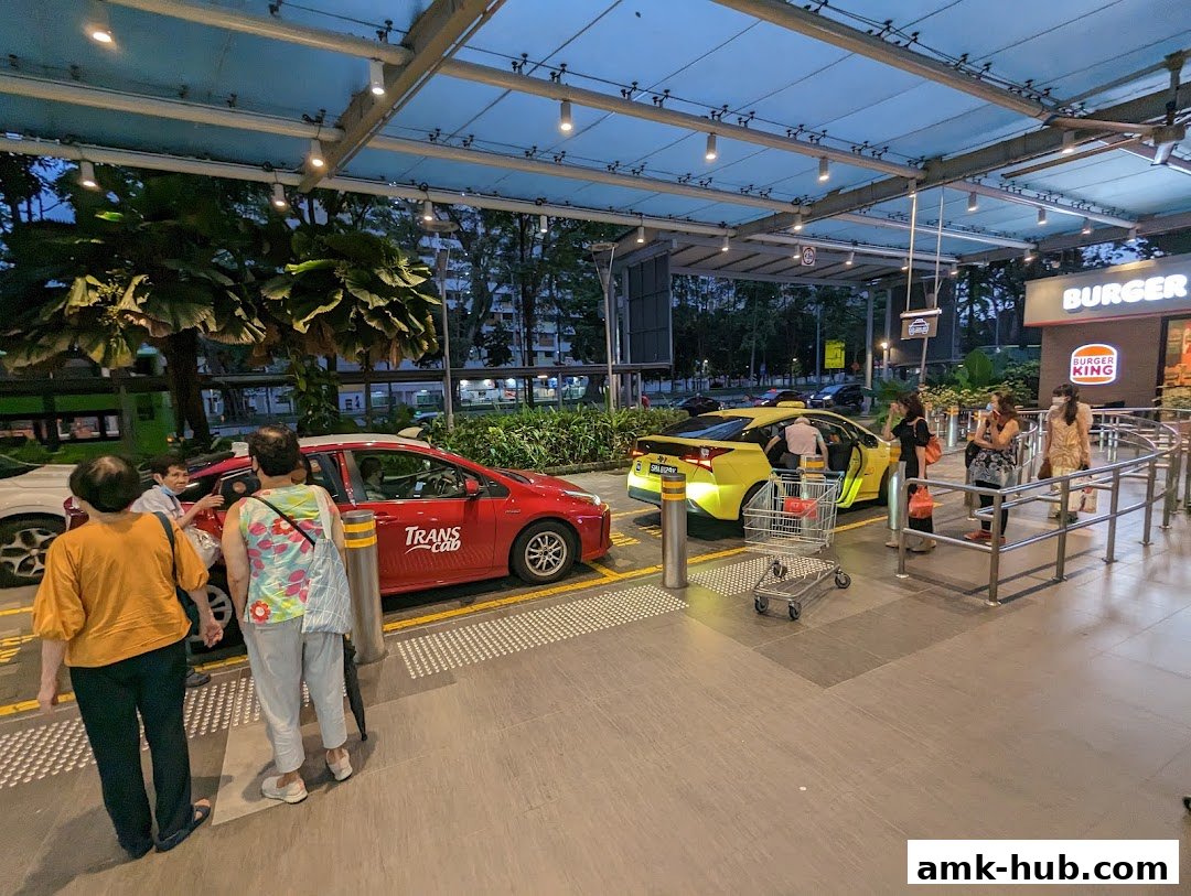 People waiting for taxis and a Burger King outlet at a covered transport hub.
