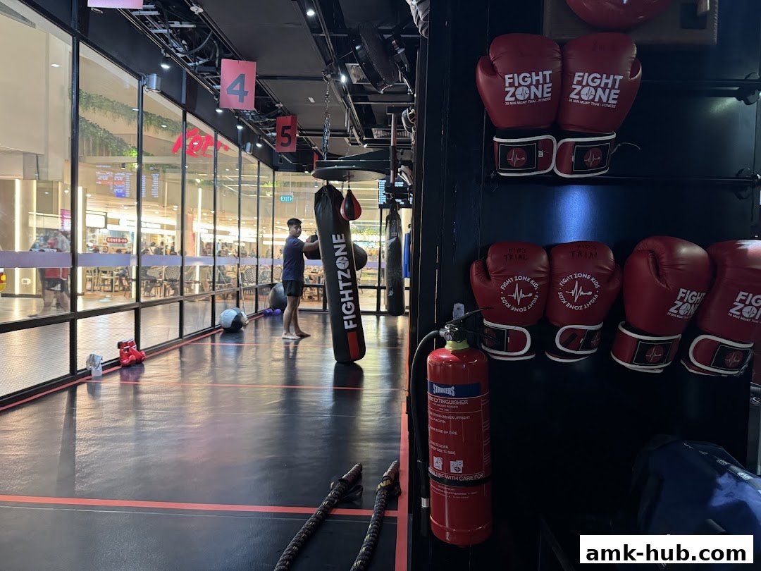 Interior of a boxing gym with punching bags, gloves, and a person training.