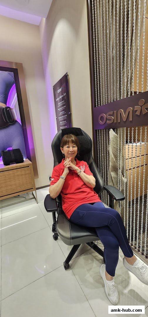 A woman sits in a massage chair in front of the OSIM store.