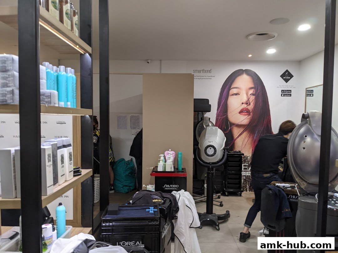 Interior of a hair salon with shelves of products and a stylist working.