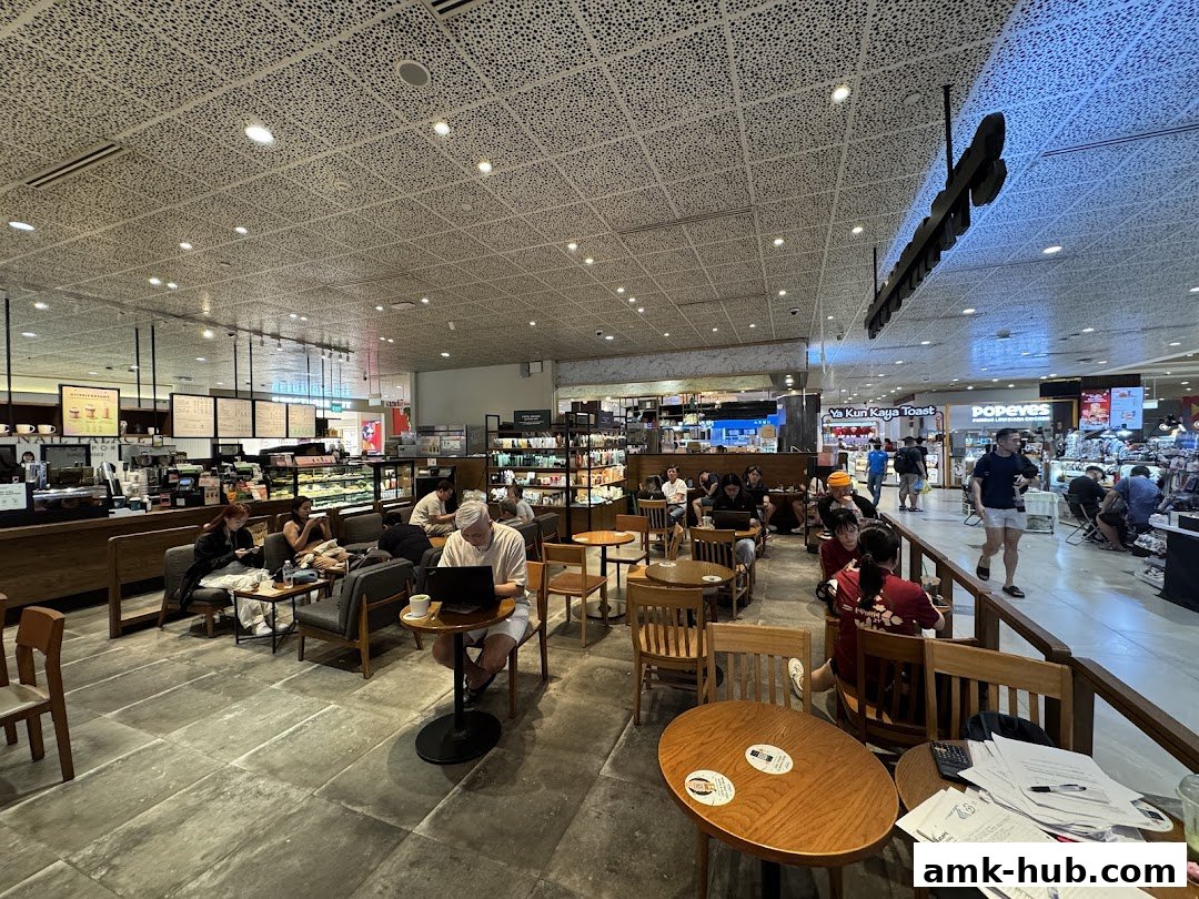 Interior view of a busy Starbucks with customers seated at tables and working on laptops.