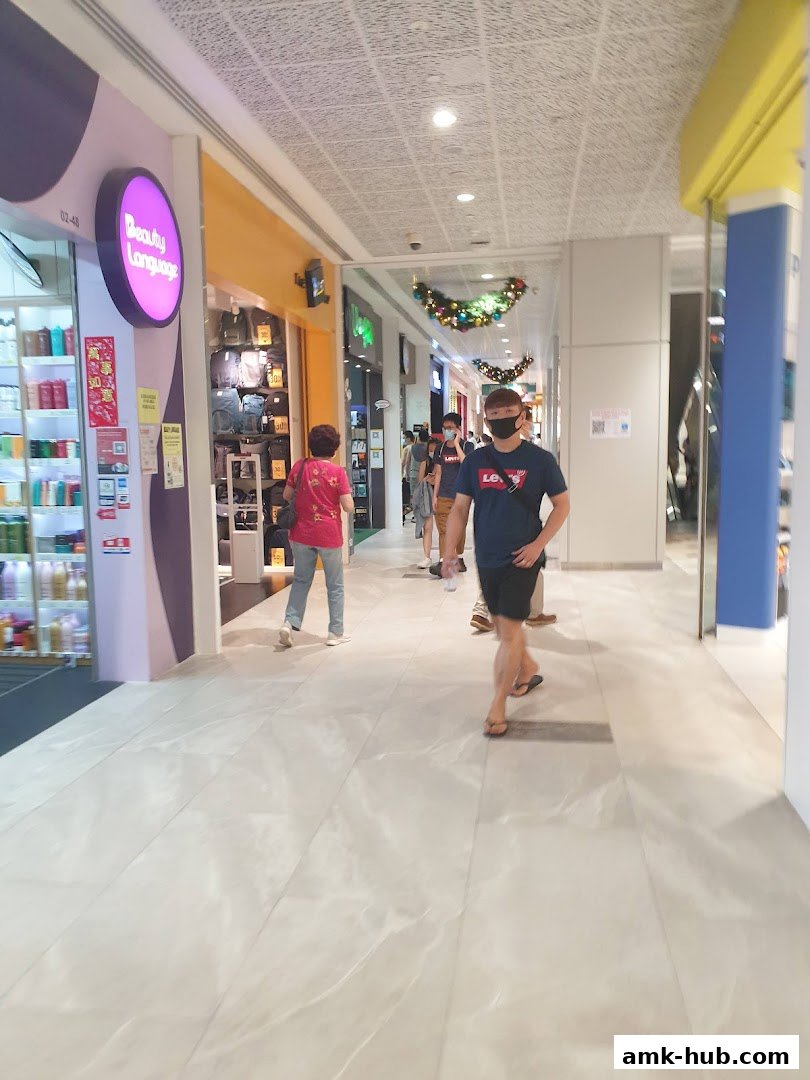 A shopping mall corridor with people walking past the Beauty Language store.