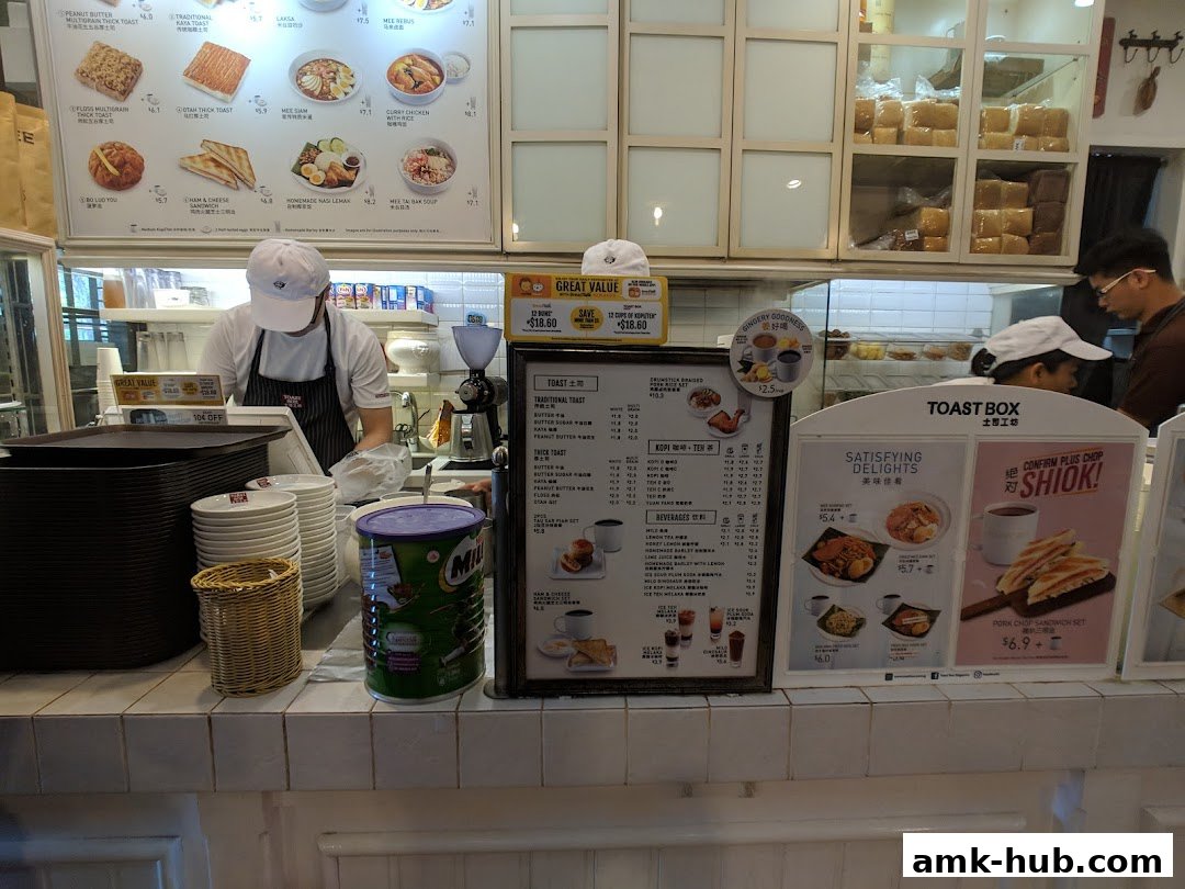 A counter at Toast Box with staff preparing food and a menu displayed.