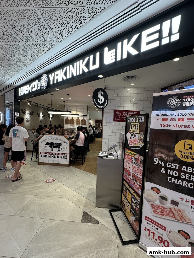 The exterior of Yakiniku Like restaurant with customers inside and promotional posters outside.