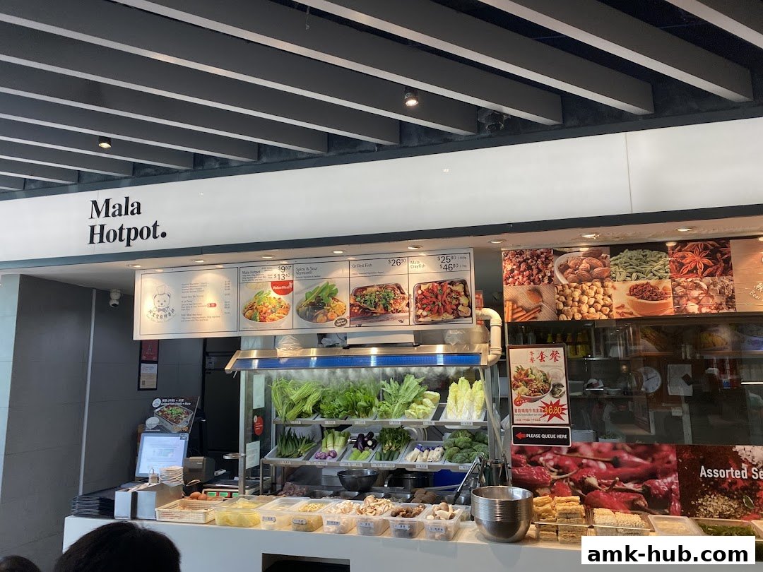 A counter display of fresh ingredients and menu items at a Mala Hotpot restaurant.