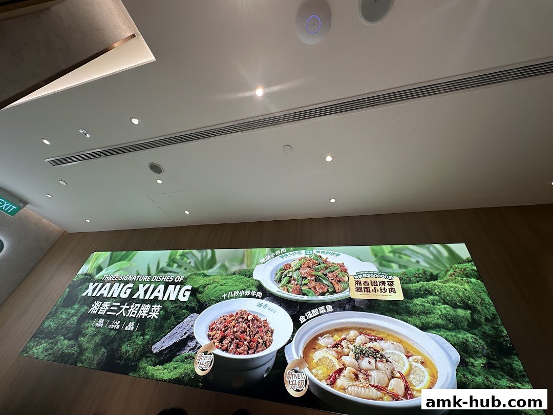 A large illuminated sign showcasing three signature dishes from Xiang Xiang Hunan Cuisine.