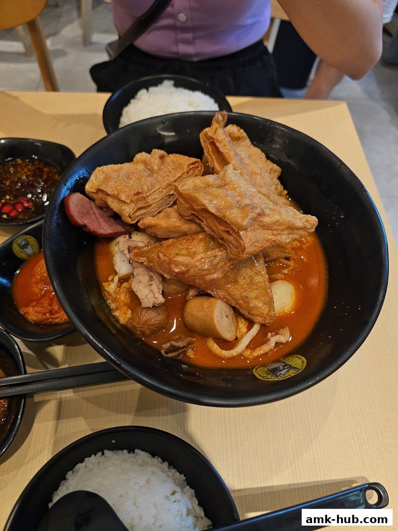 A close-up of a hearty bowl of Mala Tang with various ingredients and a side of rice.