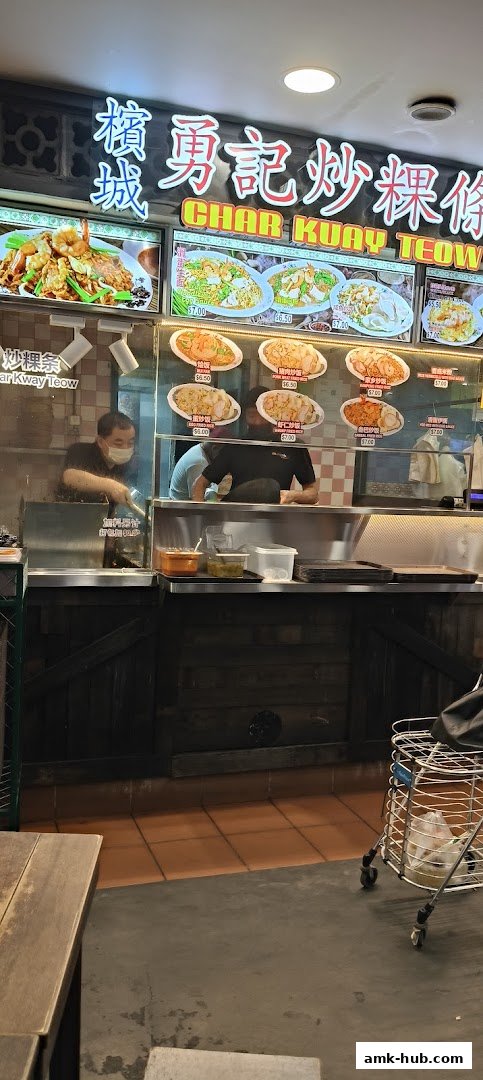 A food stall with a sign for Char Kway Teow and various dishes displayed.