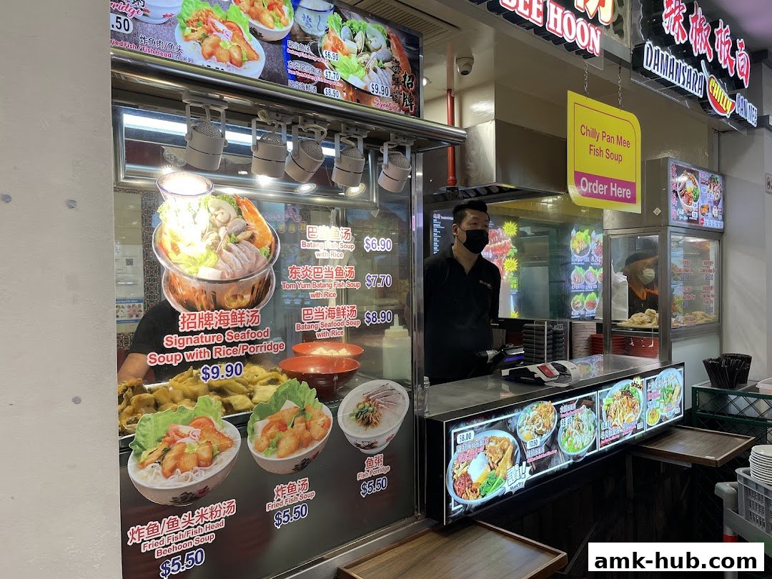 A food stall with various dishes displayed and staff serving customers.