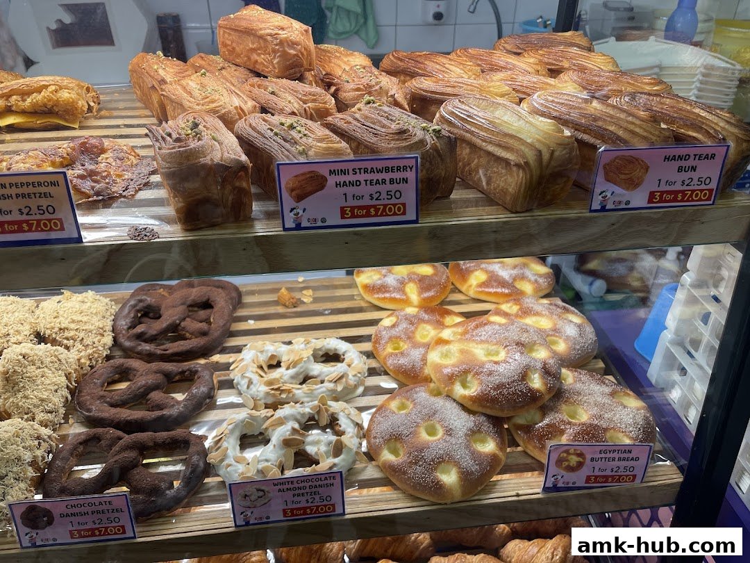 A display case filled with various freshly baked pastries and breads from CROLO by Swee Heng.