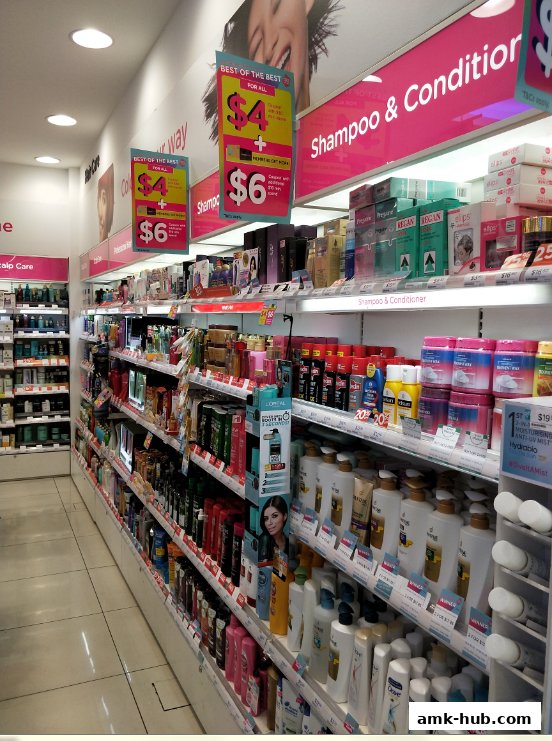 A wide aisle in a Watsons store, showcasing shelves stocked with shampoos and conditioners.