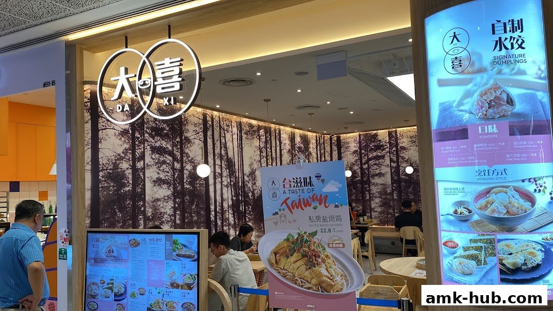 The exterior of a DaXi restaurant with a large sign and a display of signature dumplings and salted baked chicken.