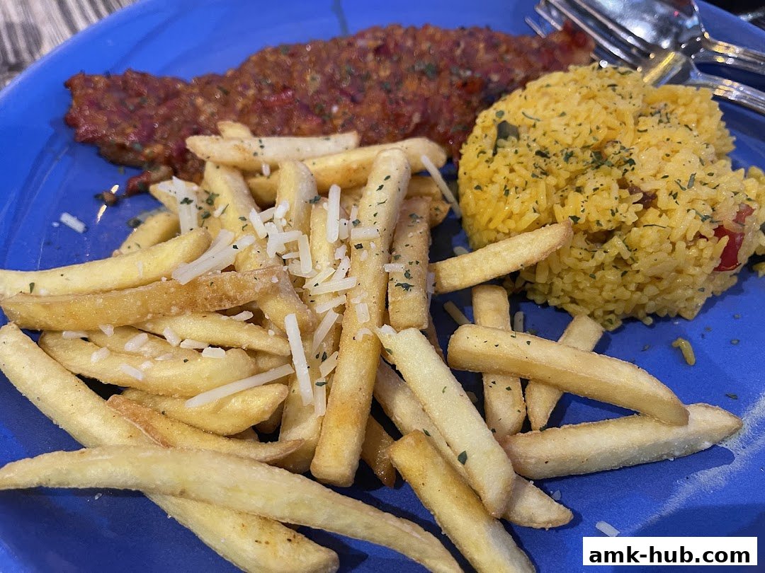 A plate of food featuring french fries, rice, and a meat dish with sauce.