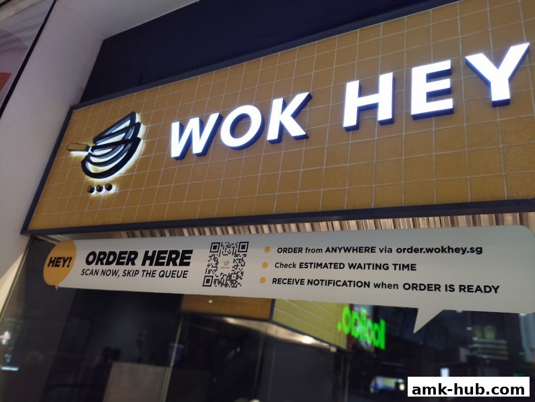 The illuminated sign for Wok Hey, a restaurant, with ordering instructions and a QR code.