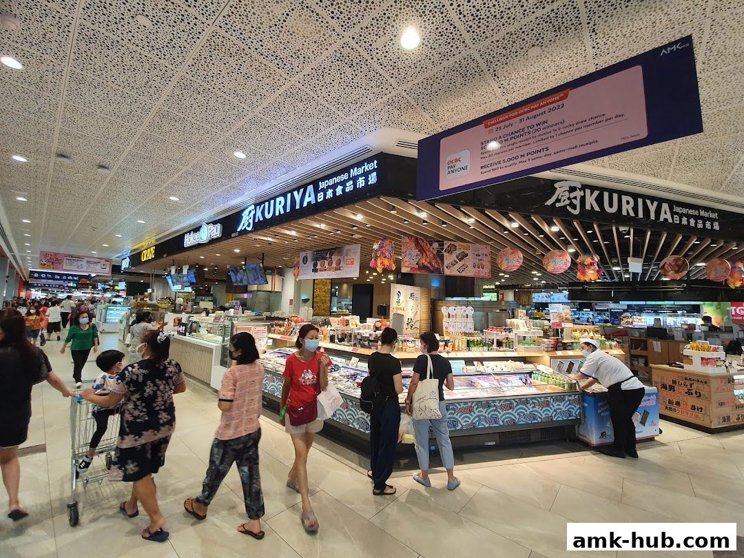 People shopping at Kuriya Japanese Market, with a promotional banner overhead.