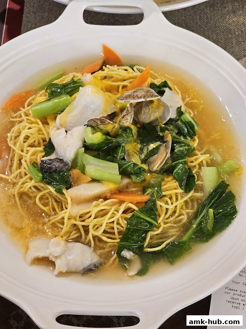A close-up of a delicious seafood noodle dish with fresh vegetables and fish.