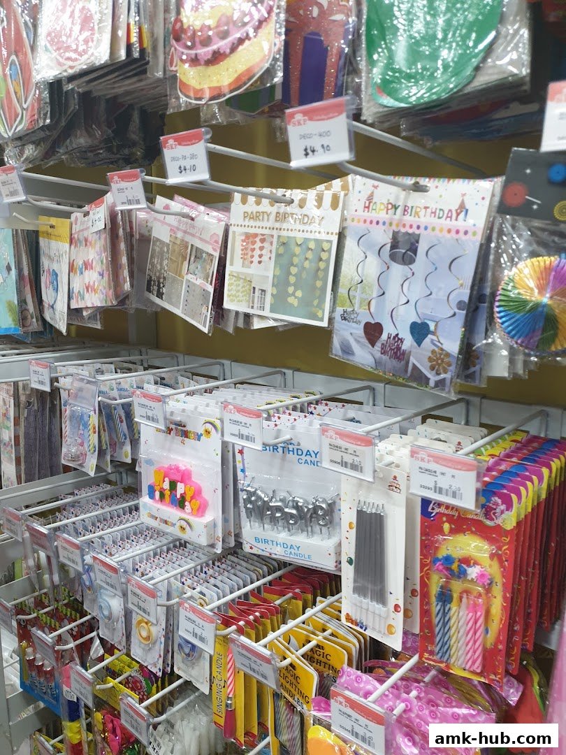 Shelves stocked with birthday party decorations and candles, including banners and various types of candles.
