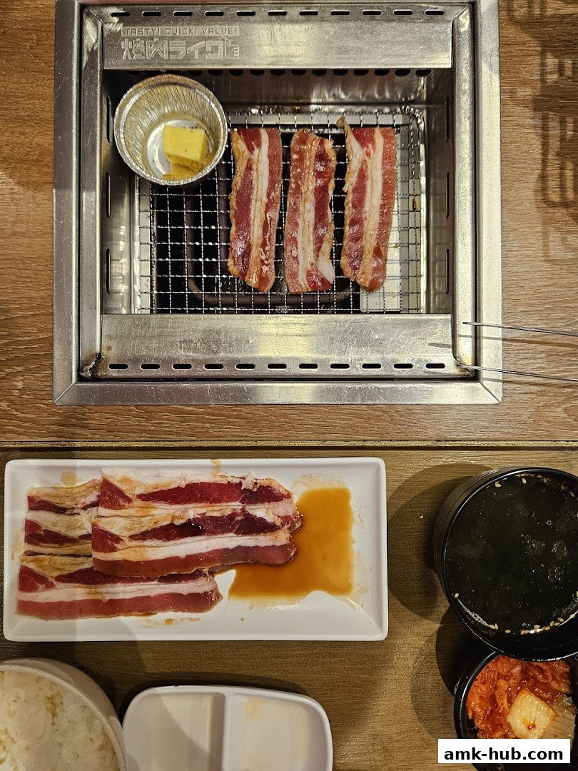 Sizzling strips of marinated meat grilling with butter and side dishes of rice, soup, and kimchi.