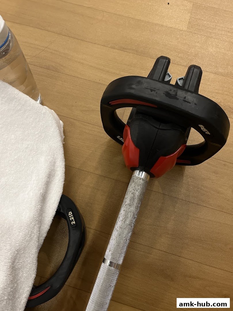A barbell with weight plates and a towel on a wooden floor.