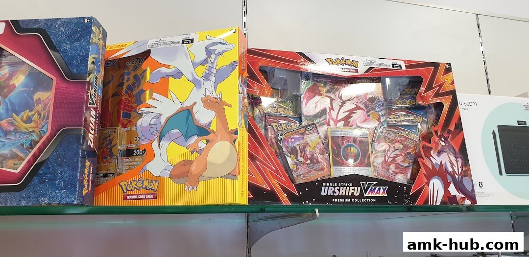 Pokemon trading card game boxes and a Wacom tablet are displayed on shelves.