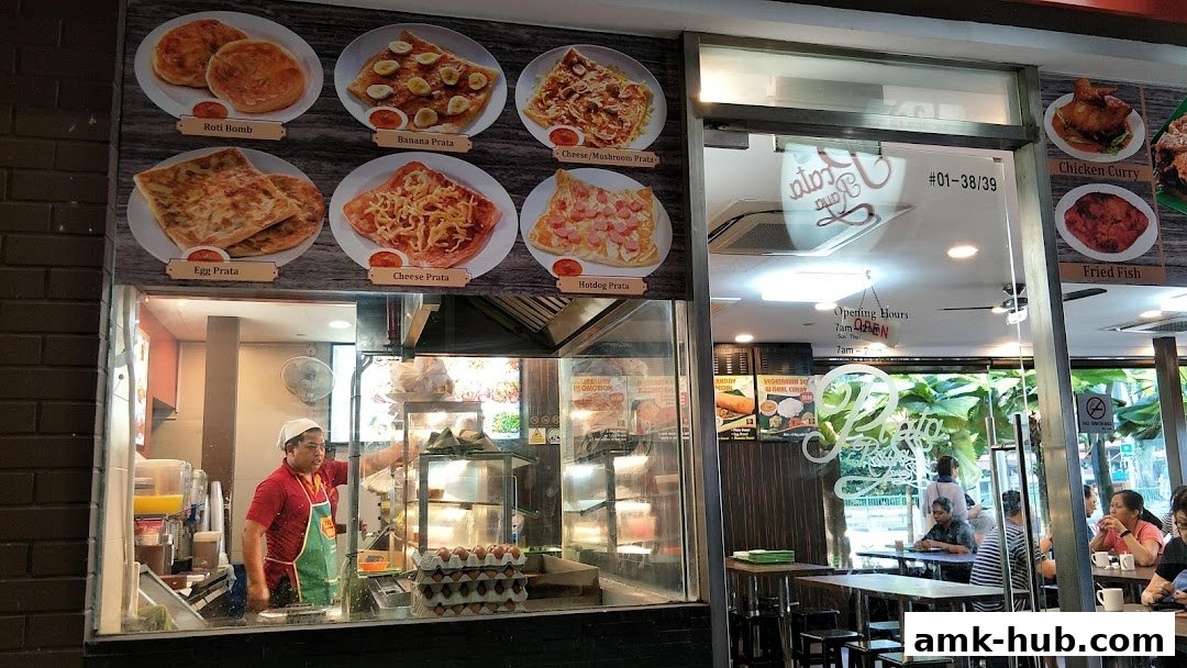 A restaurant storefront displaying various prata dishes and menu items, with staff visible inside.
