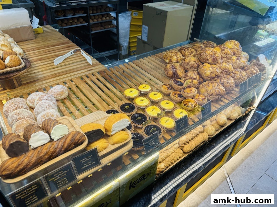 A display of various pastries including tarts, cream puffs, and bread at a bakery.