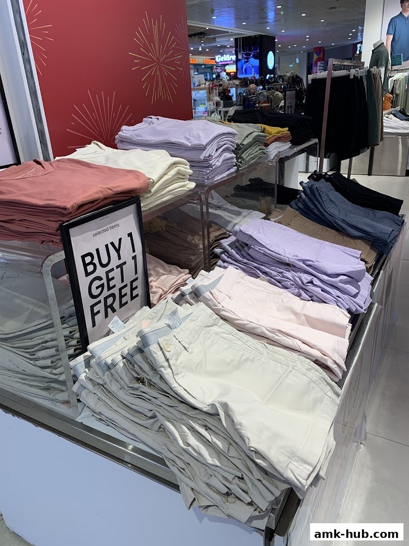 Neatly folded stacks of casual wear, including t-shirts and shorts, displayed in a retail store.