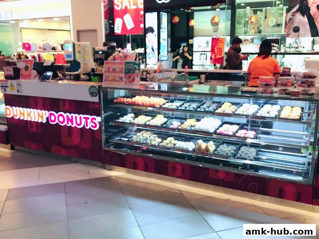 A Dunkin' Donuts counter displaying a wide variety of colorful donuts in a display case.