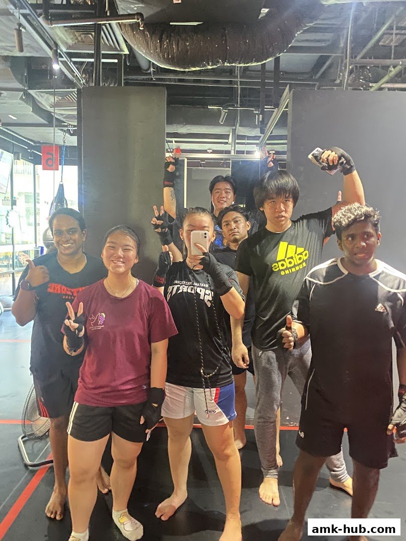 A group of people posing for a selfie in a gym, likely after a training session.
