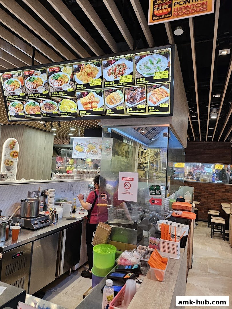 A brightly lit menu board displaying various noodle dishes and side items at Pontian Wanton Noodles.