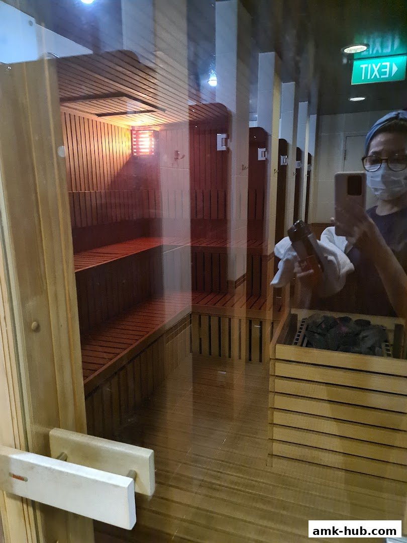 Interior view of a clean and modern sauna with wooden benches and a person taking a photo.