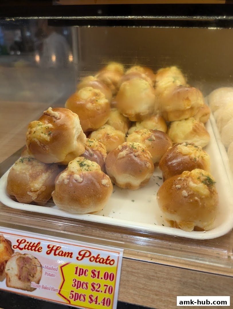 A display of freshly baked savory buns with a price tag for 'Little Ham Potato'.