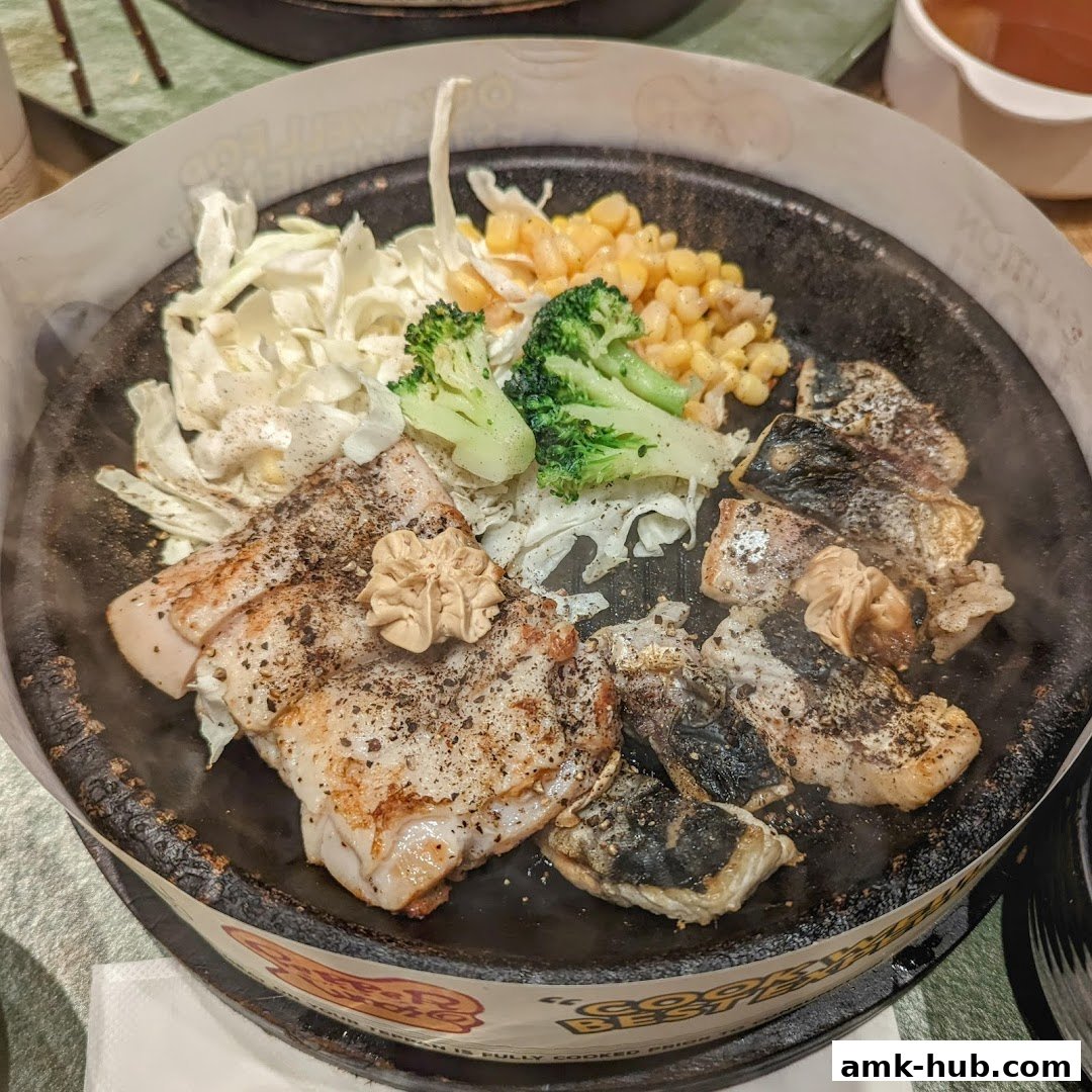 A sizzling hot plate of fish with vegetables and butter.