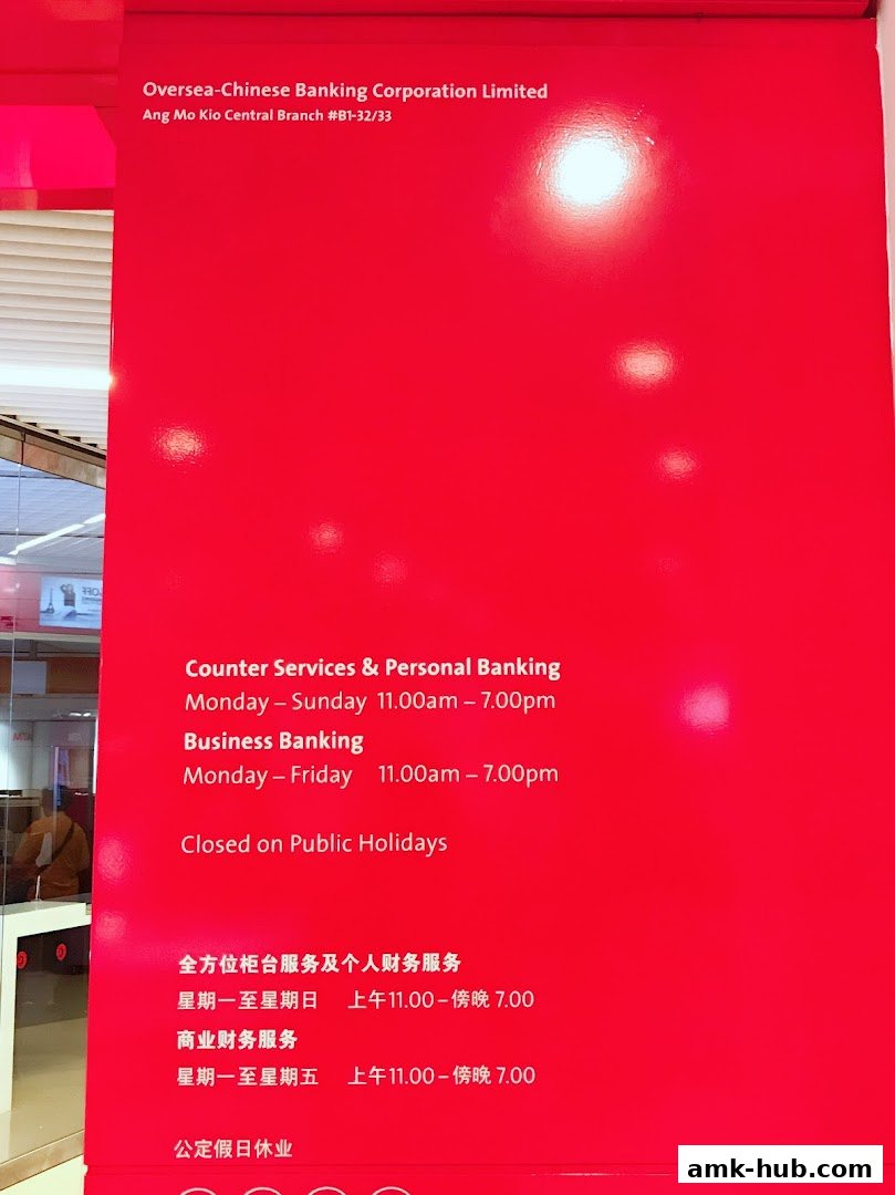 A red wall displays operating hours for OCBC Bank Ang Mo Kio Central Branch.