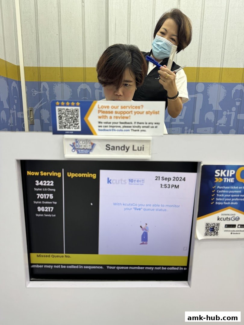 A stylist is cutting a customer's hair while a queue management screen is visible.