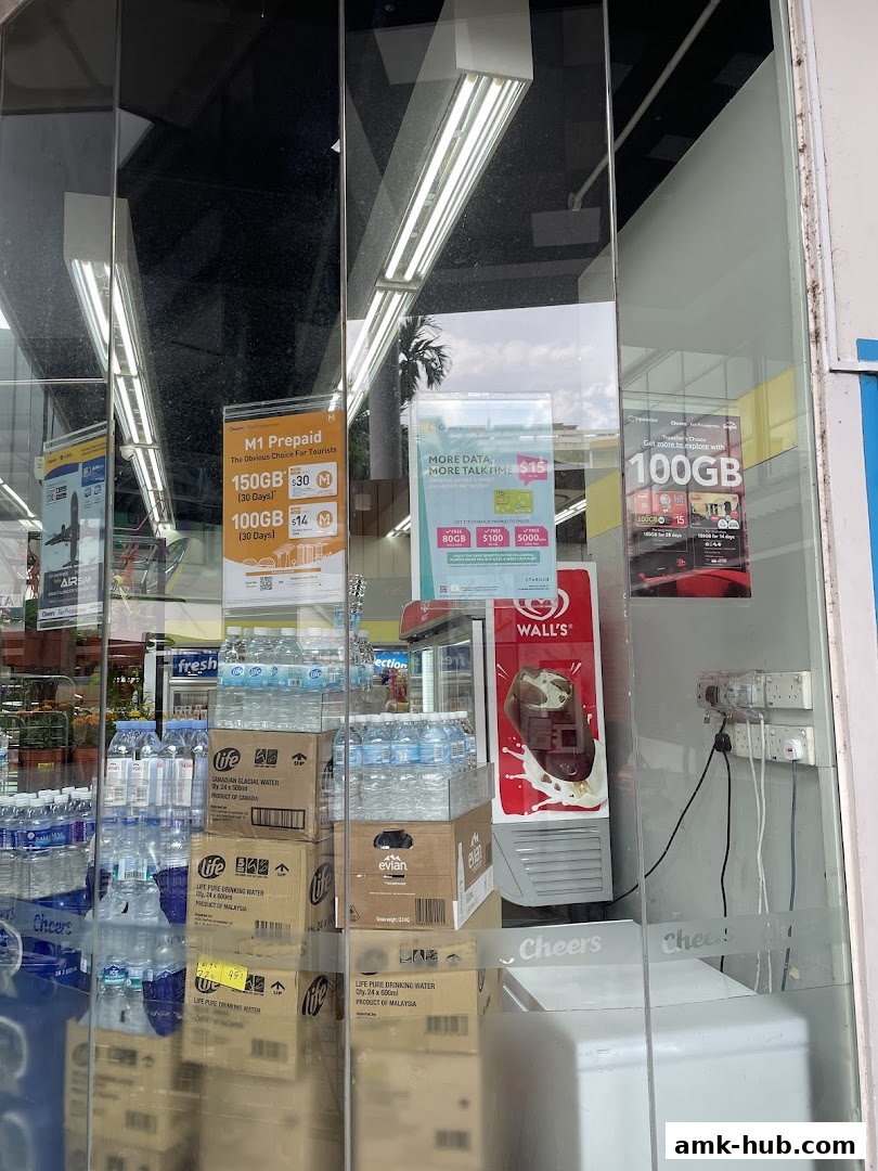A shop window displaying mobile plans, bottled water, and a Wall's ice cream freezer.