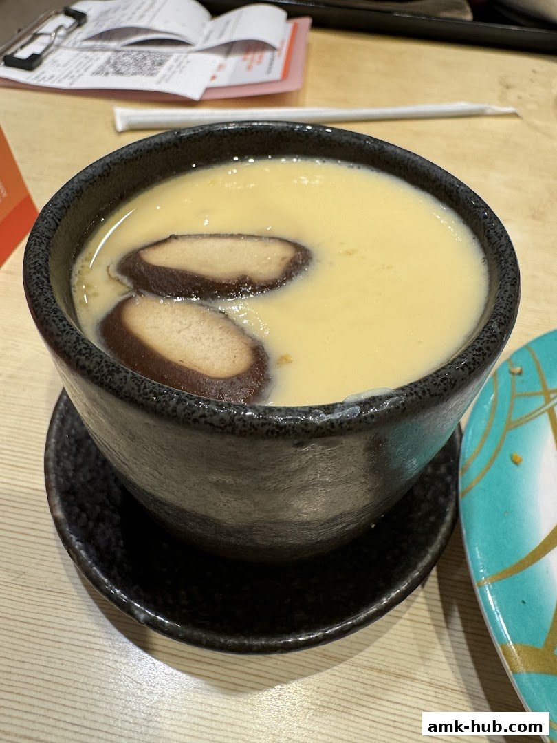 A close-up of a steaming bowl of chawanmushi with shiitake mushrooms.