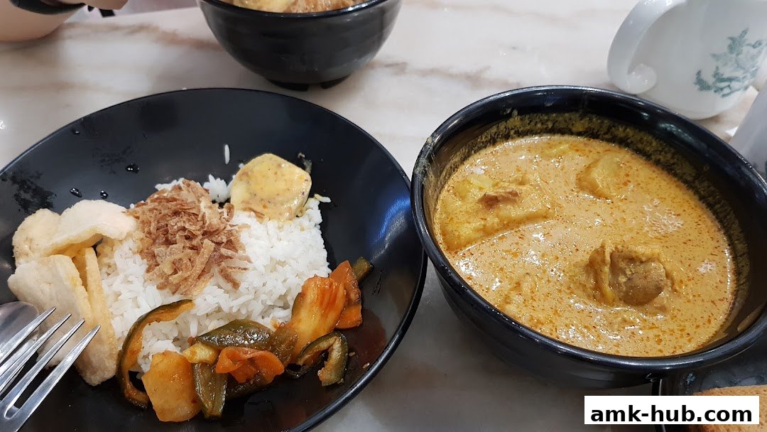 A close-up of a delicious curry dish with rice, crackers, and vegetables.