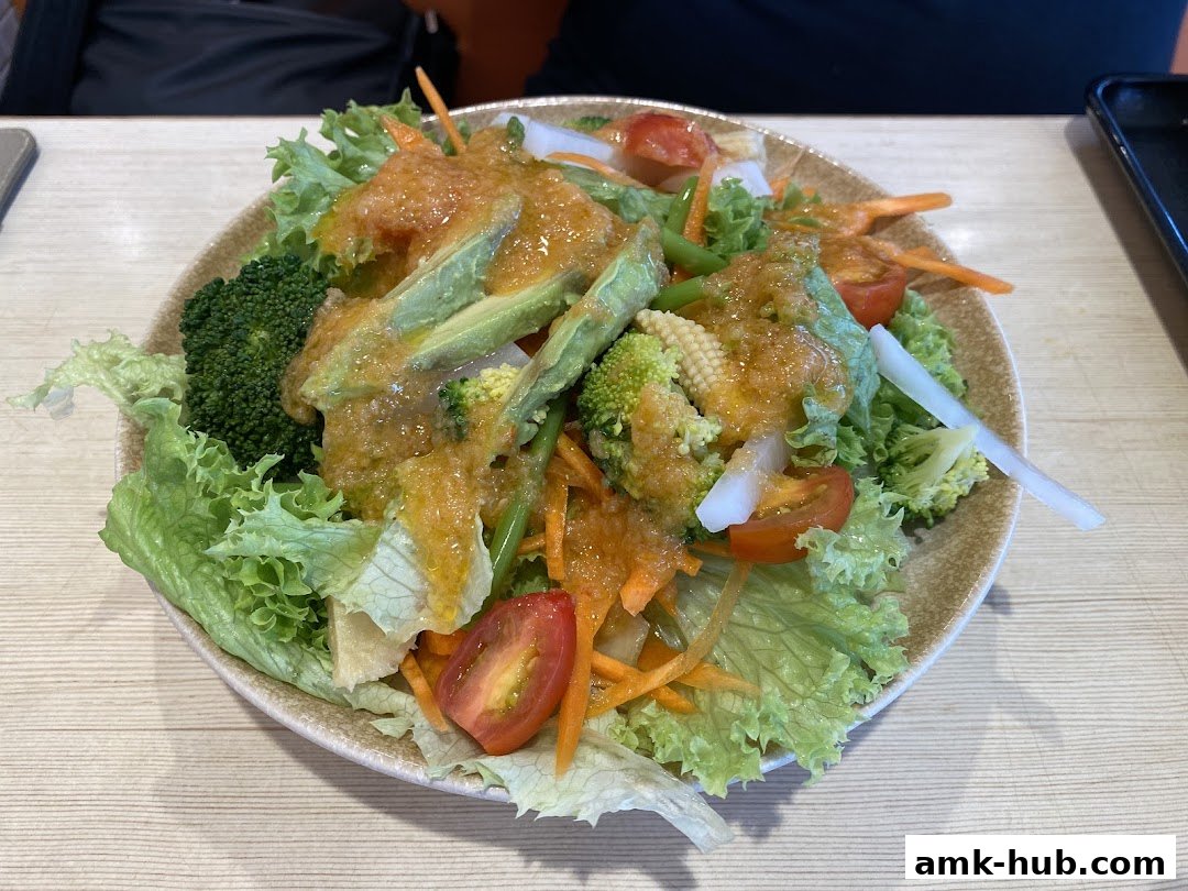 A vibrant salad with fresh lettuce, broccoli, avocado, tomatoes, and carrots, drizzled with dressing.