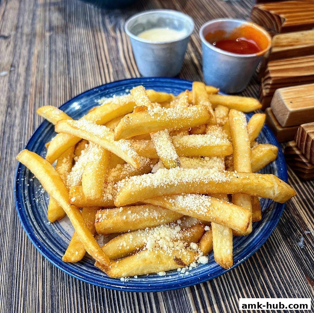 A plate of golden french fries topped with grated cheese, served with dipping sauces.