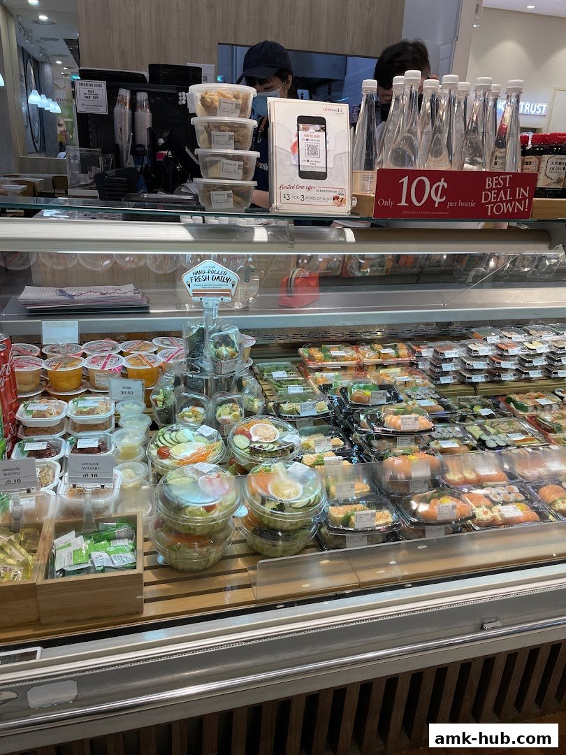 A display case filled with pre-packaged sushi, salads, and drinks at a food stall.