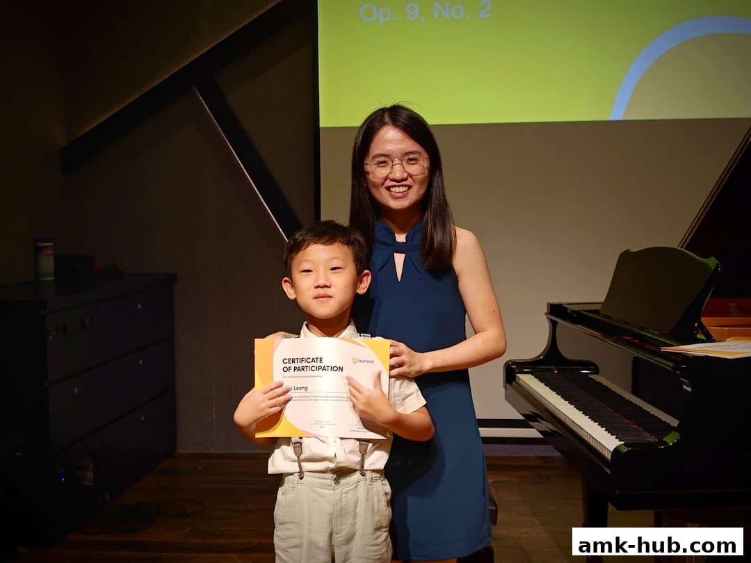 A teacher presents a certificate to a young student in front of a piano.